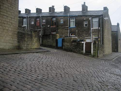 Photo of cobbled path leading up between the back yards of two rows of small houses