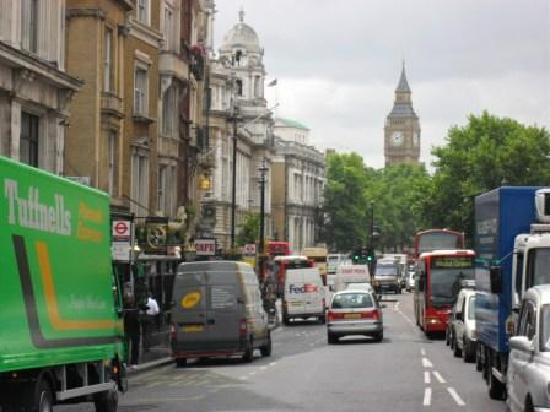 broad street of small shops looking towards green trees and Big Ben in the far distance