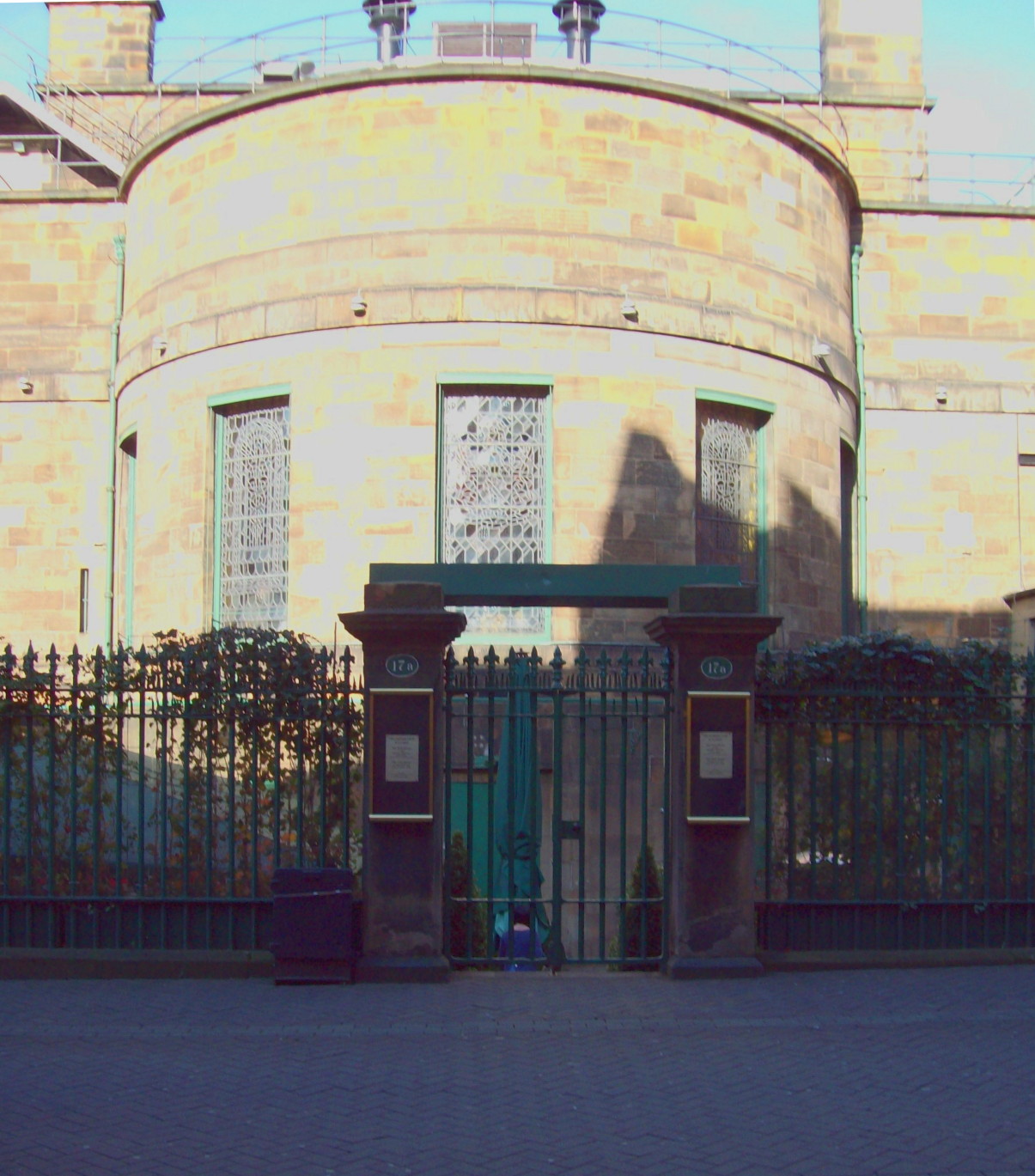 open, square archway from cobbled street into courtyard, with a rounded stone tower showing beyond