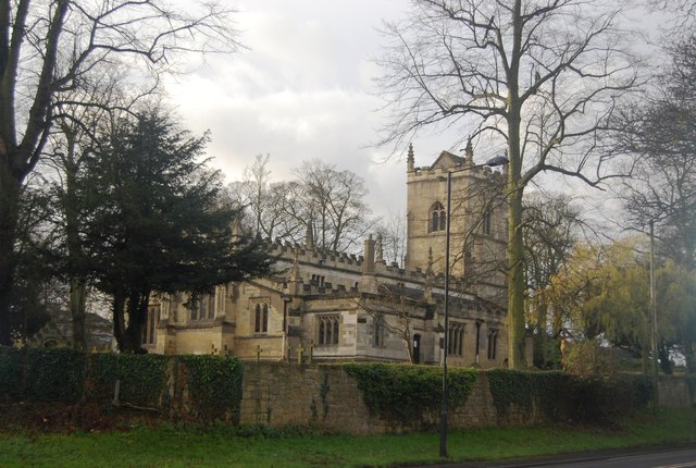 elaborate church with a square tower and crenellated roof-line, surrounded by a low stone wall and scattered trees