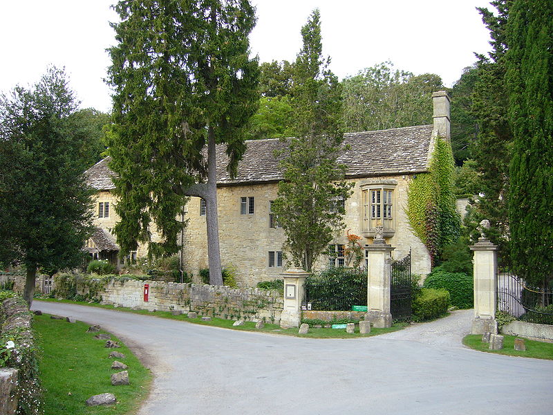 wrought-iron gates next to a very old-looking cream stone house