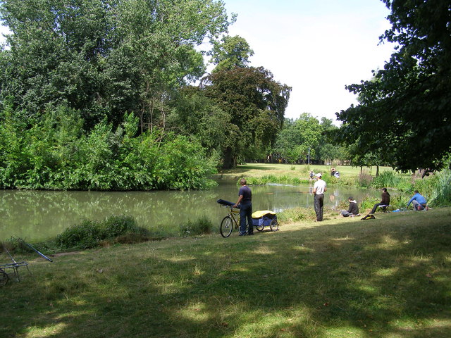 small lake surrounded by trees, with people looking at it