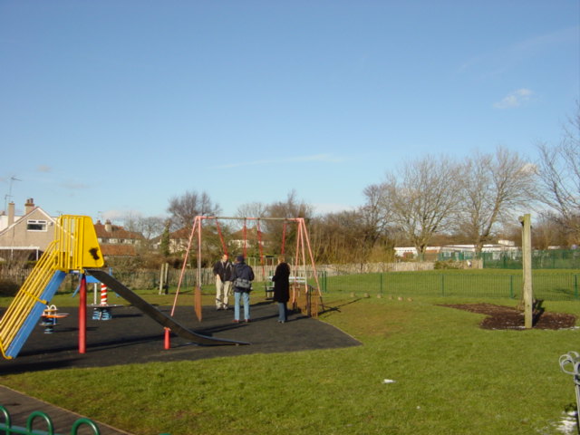 children\'s swings and slide in the corner of a park