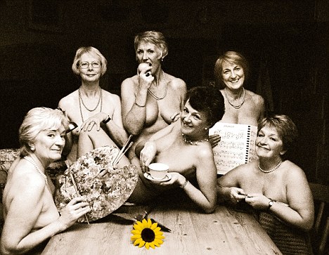 photo showing upper bodies of six naked middle-aged women seated around a table, all in greyscale apart from a yellow sunflower lying on the table