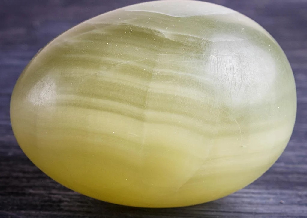 photograph of a stone egg made of smudgily-banded green and cream onyx