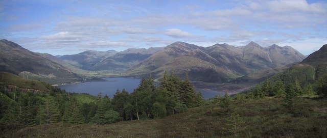 panoramic view down across a loch towards a very bare, wild mountain range