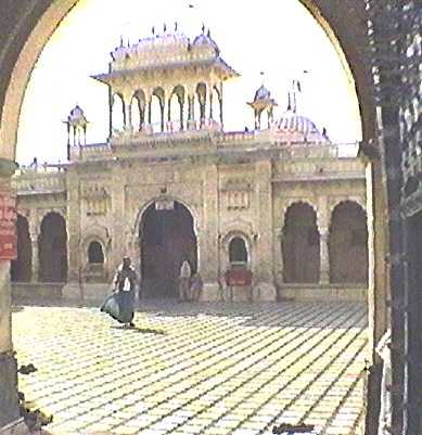 Shot taken standing under archway looking across brick-floored open courtyard towards elaborate marble entrance