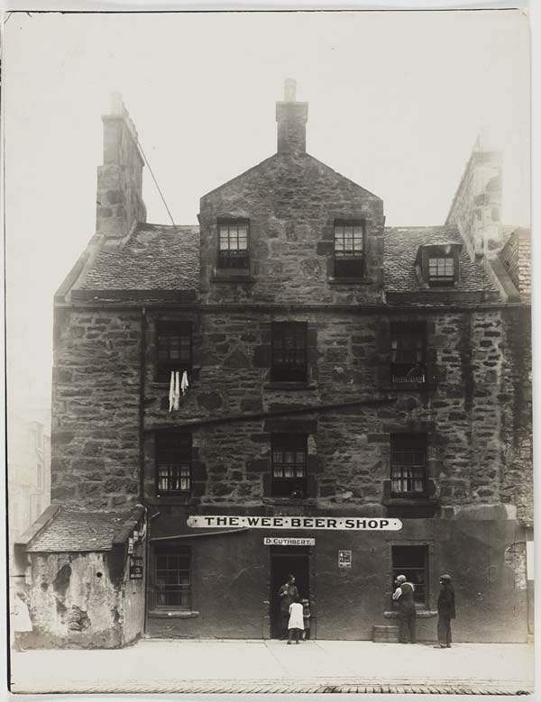 faded greyscale photo\' of dark stone four-storey building with a shop called \'The Wee Beer Shop\' on the ground floor and gables crossing at right angles