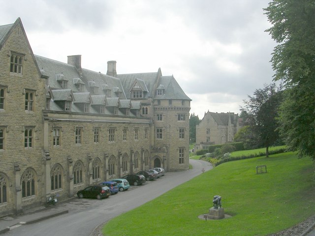 long four-storey building in grey-brown brick with a slate roof, two of the storeys being actually in the slope of the roof itself. With Mediaeval-style arches over the ground-floor windows, and a sweep of grass to the right