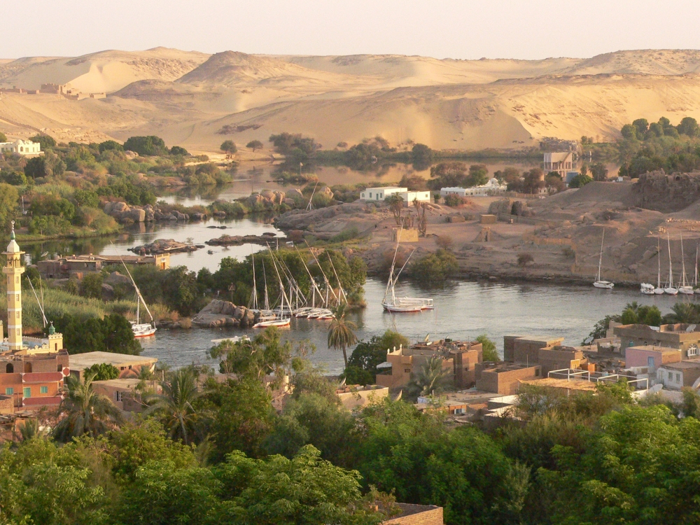 view from a high place down across a wide river tangled with islands, greenery and buildings, with bare golden hills in the background