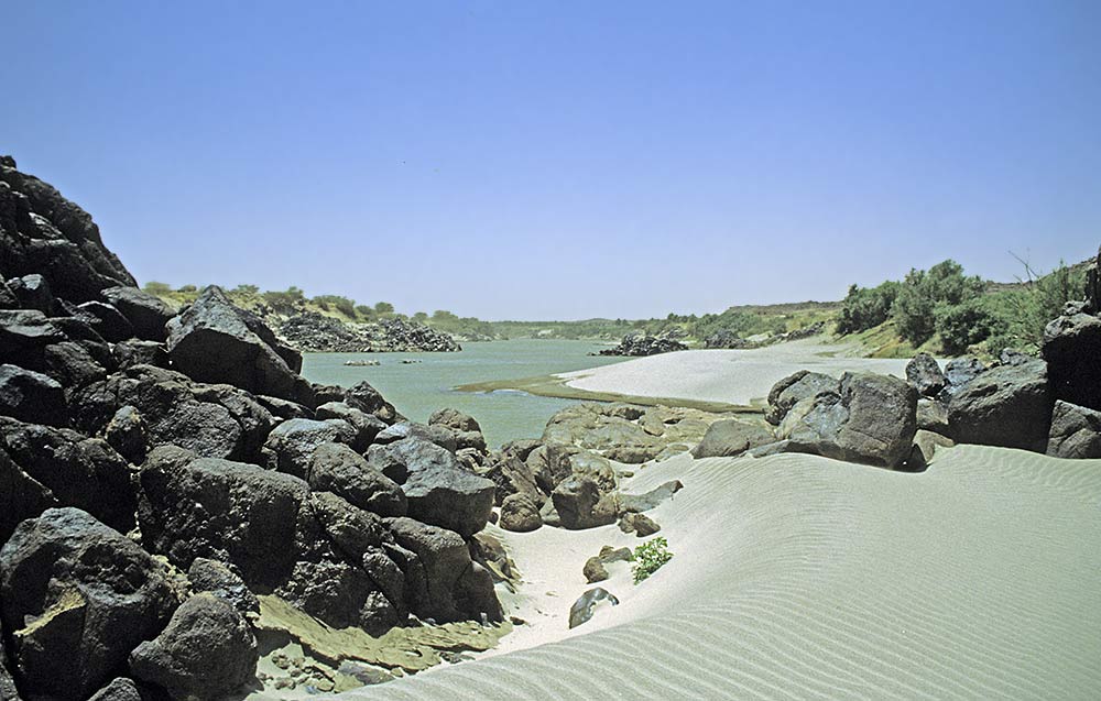 river winding past high black rocks on the left