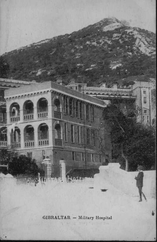 greyscale photo\' of a blocky oblong three-storey building, building with a high wooded slope behind it: the end wall of the upper two storeys is pierced with arched colonades