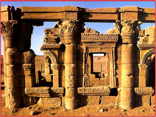 a row of golden sandstone pillars in front of a window into a now-roofless building