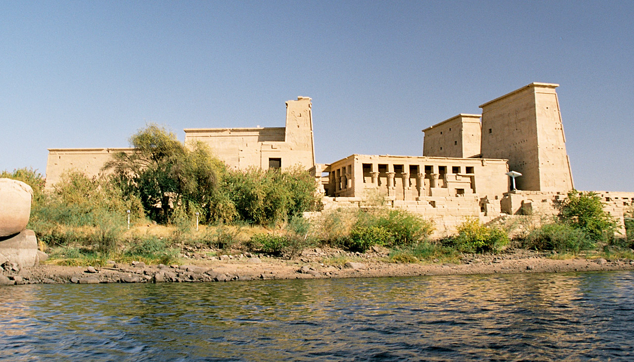 blocky temple made of golden stone, on a lake-shore dotted with bushes