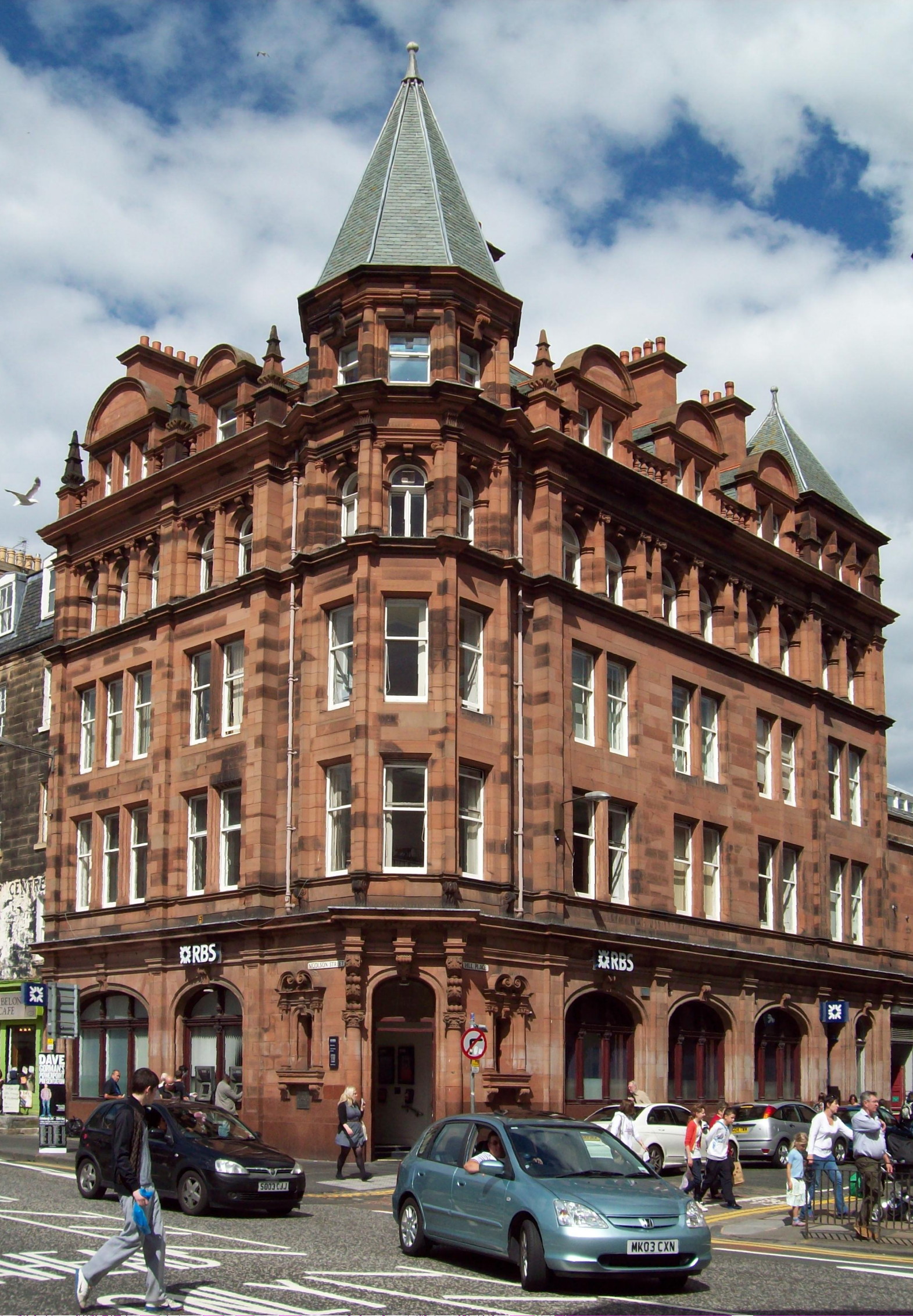 modern photograph of a tall brown building crowned with a spire, seen corner-on