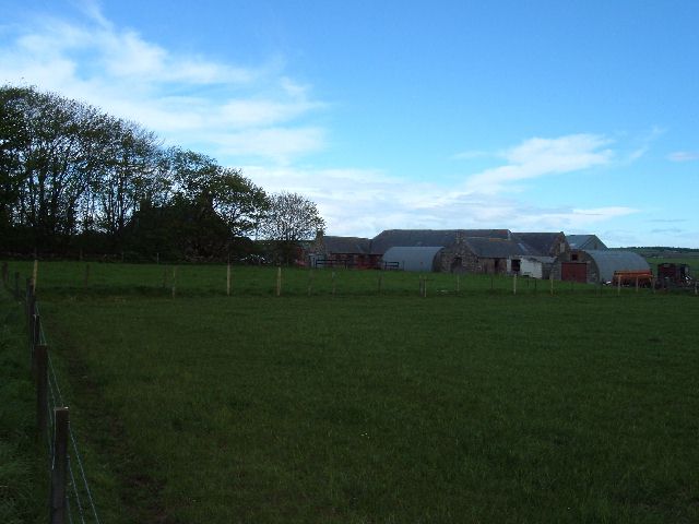 small farm skylined across a green slope at dusk