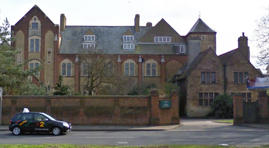 large irregular early 20th C red-and-cream brick building behind a low wall