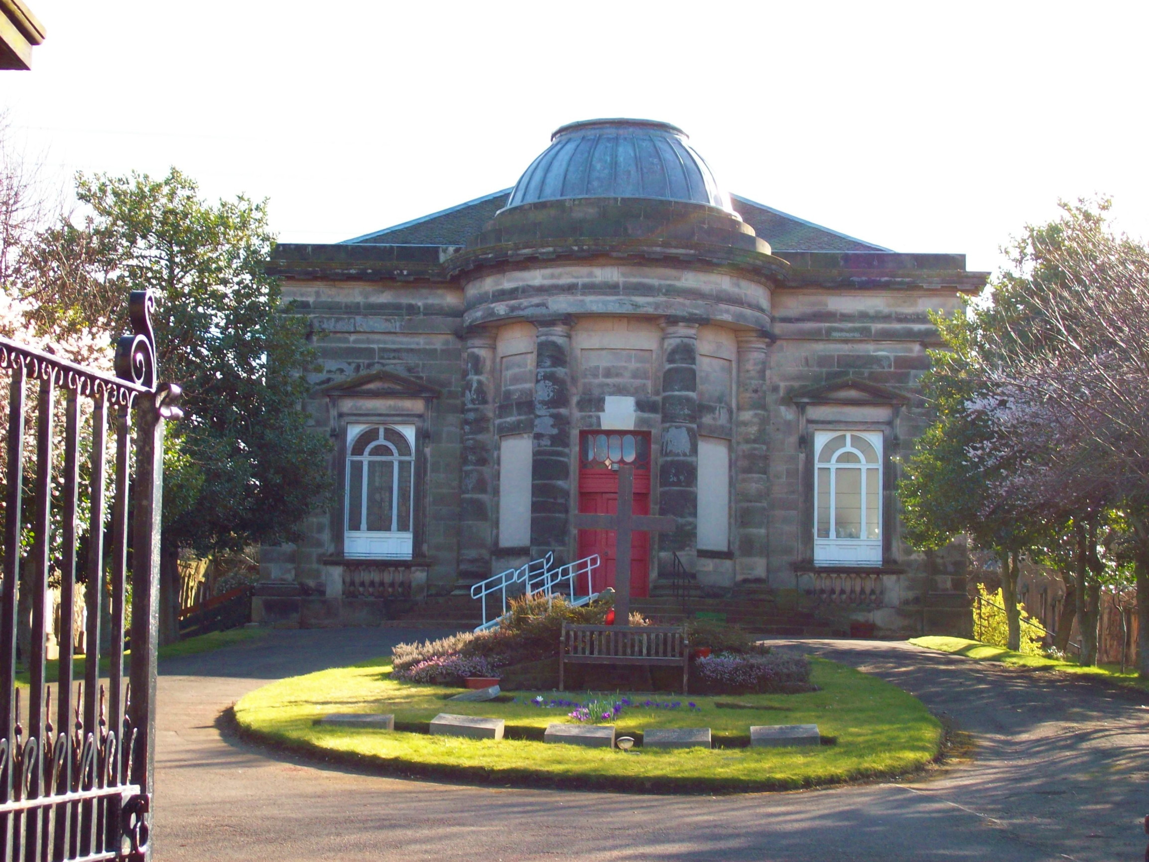 view across a formal garden to a small square Georgian church with windows like surprised eyes, and a massive round porch with pillars