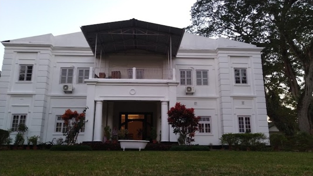 large, white 1920s-ish two-storey building with a square entrance recessed between pillars with a covered balcony above