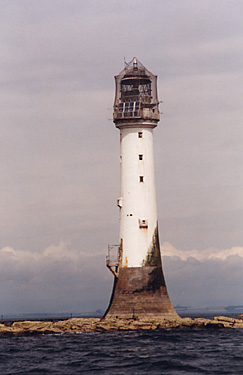 view of lighthouse standing on a thin layer of rock, barely above water