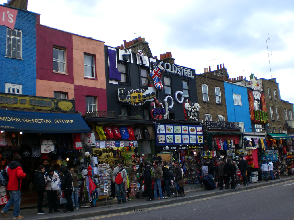 street of shops painted full-height in bright colours, many decorated with sculptured signs