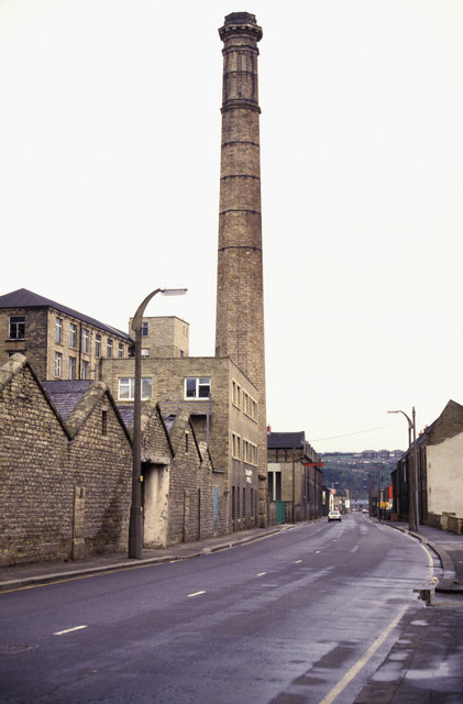 photograph of shabby industrial buildings with towering factory chimney in background