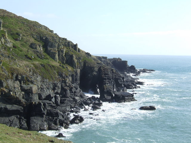 view of crumbly-looking black cliffs battered by the sea