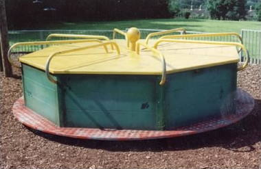 octagonal wooden box about 6ft across and 2ft high, with blue sides and a yellow top, divided into eight seating areas by yellow hand-rails, the whole being mounted on a turntable