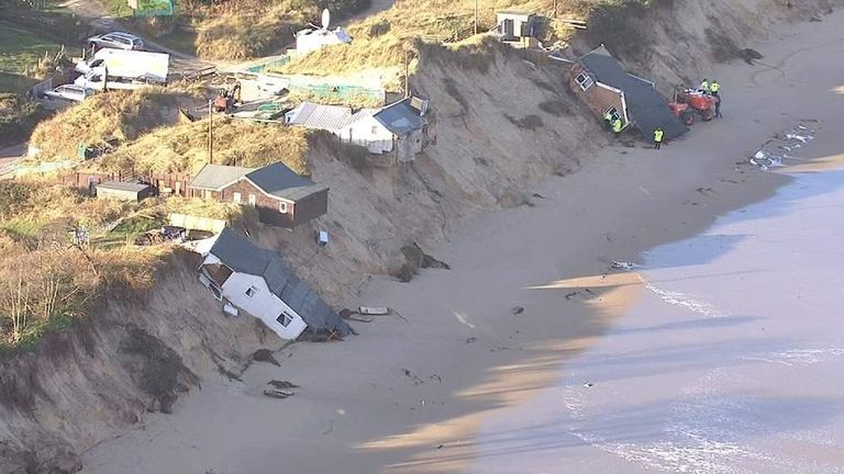 Photo of small houses collapsing onto a beach