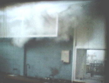 puff of smoke hovering above a laboratory bench next to a fume cupboard