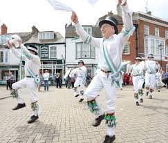 Photo of dancers in white leaping and waving handkerchies in a traditional town square