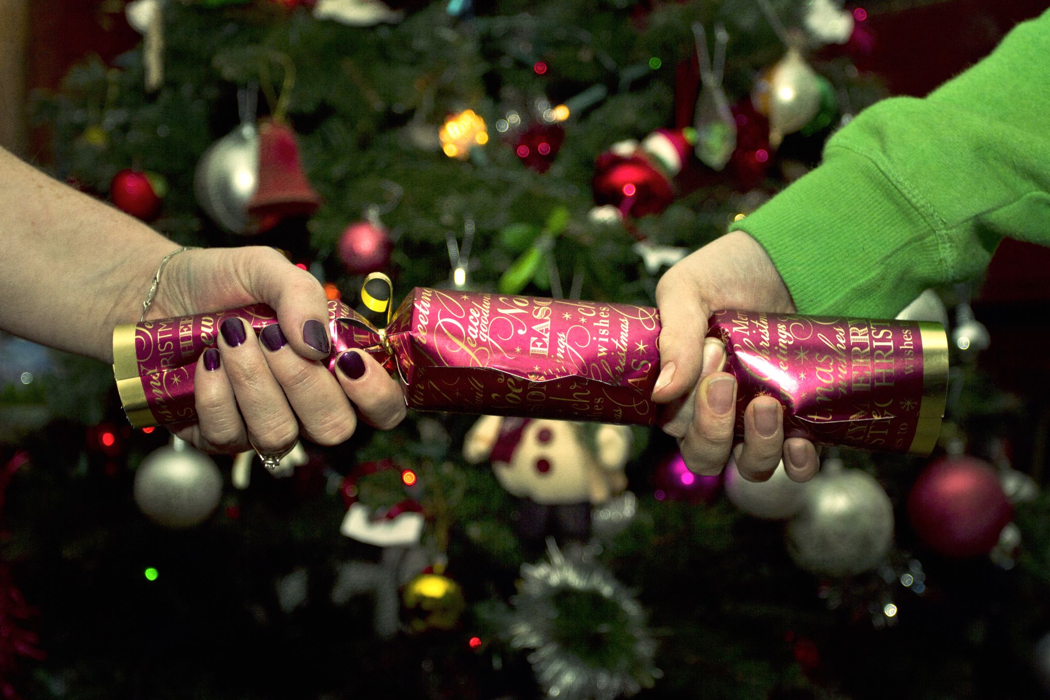 Photo of two hands pulling a maroon Christmas cracker