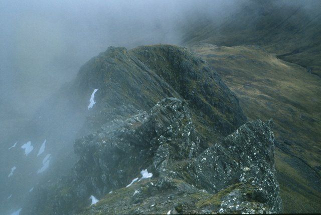 looking down through mist to a jagged ridge of rock