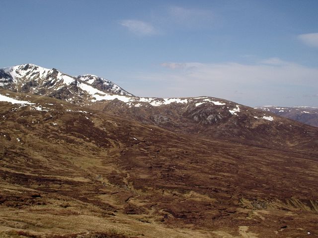 brown moorland sloping down from left to right, with snow-capped mountains seen beyond it
