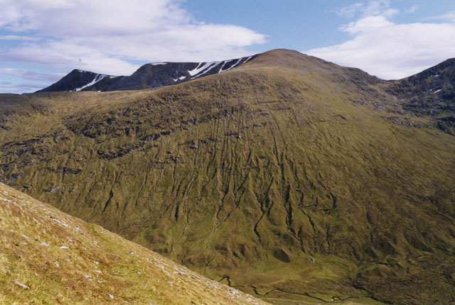looking from a high place across a green-gold valley towards a mountain peak