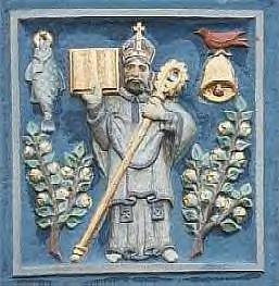 painted low-relief plaque showing a bishop surrounded by trees, a fish, a bird and a bell