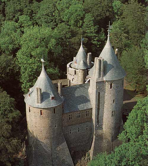 small squat rebuilt castle with conical-roofed towers