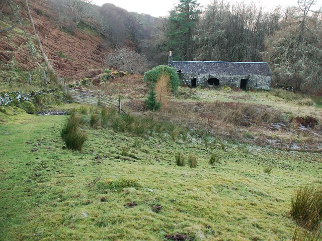 rather scrubby pasture-land on a steep slope, with an empty stone barn in the background