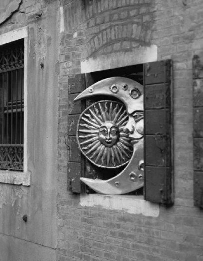 greyscale shot of cupboard-door opened to show plaques in the form of a stylised sun and moon