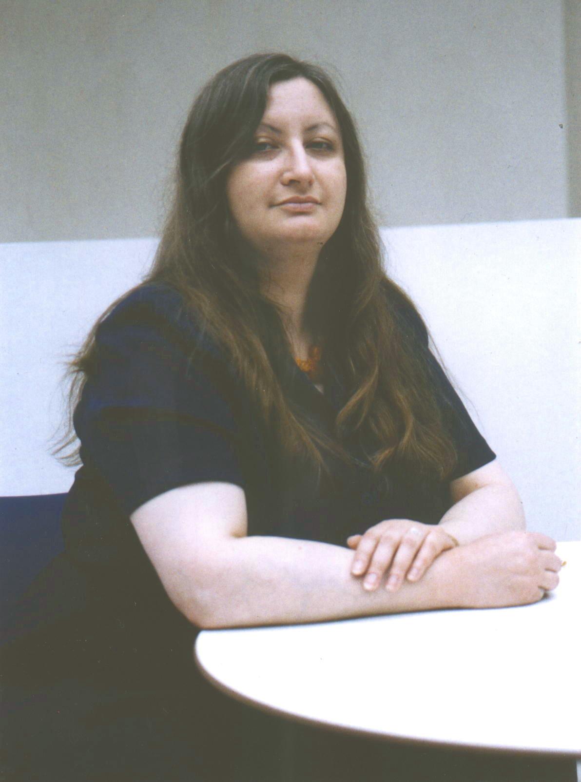 Claire Jordan, seated with arms resting on table