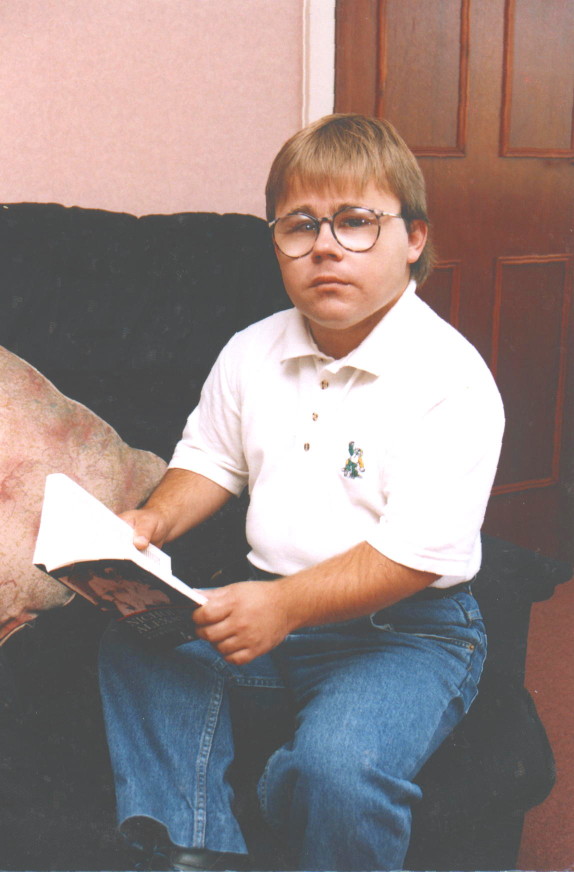 Eric Cullen on sofa, holding book: one of two photo's which originally accompanied article in The Big Issue