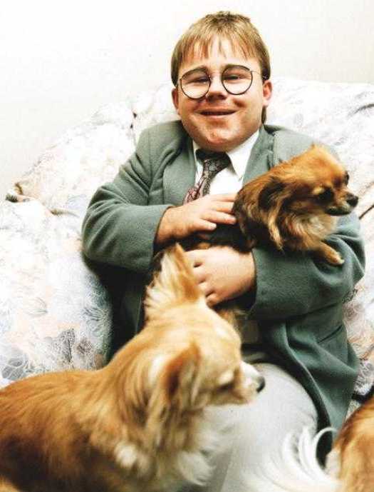 Eric Cullen on sofa, with three long-haired Chihuahuas and weird grin