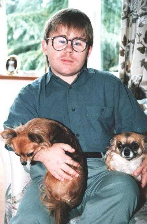 Eric Cullen on sofa, with two long-haired Chihuahuas and incipient moustache