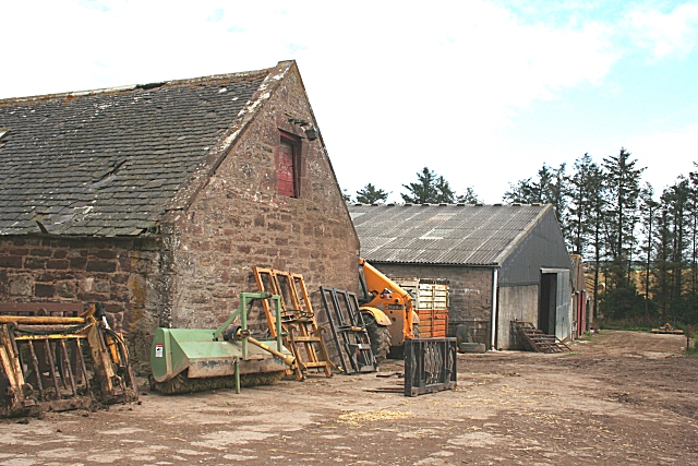 two barns, one old, one fairly modern, surrounded by agricultural machinery