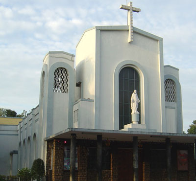 white blocky Art Deco-style church trimmed with grey-painted arches and a statue of Jesus