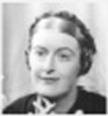 black and white full-face photo\' of a woman of about forty with a square jaw, arched brows and a heavy coil of rich blond hair, wearing a dark top