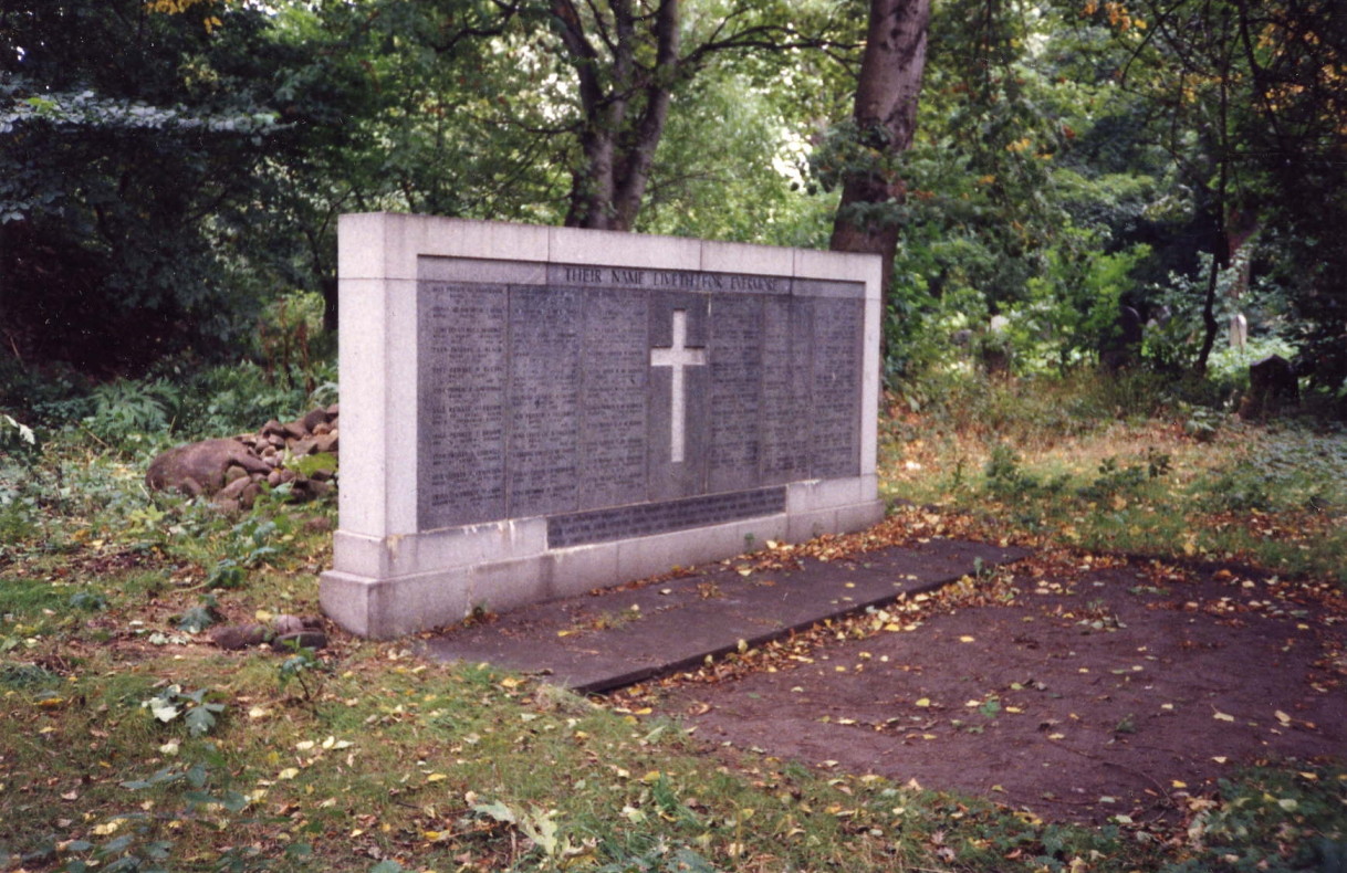 oblong grey and white stone memorial bearing a cross and a list of names, with tangled woodland behind it