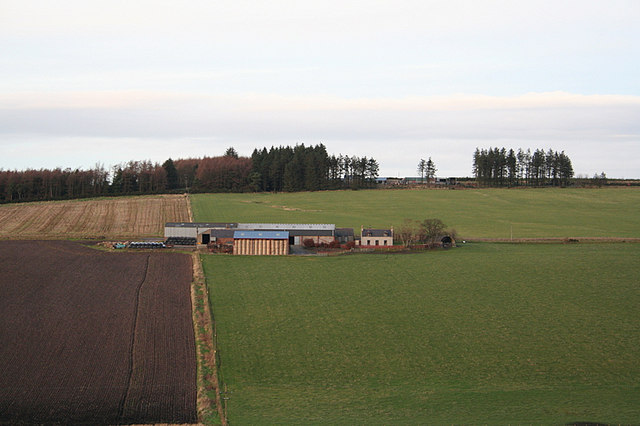 small farm with tiny white farmhouse, viewed hin the distance across brown and green fields