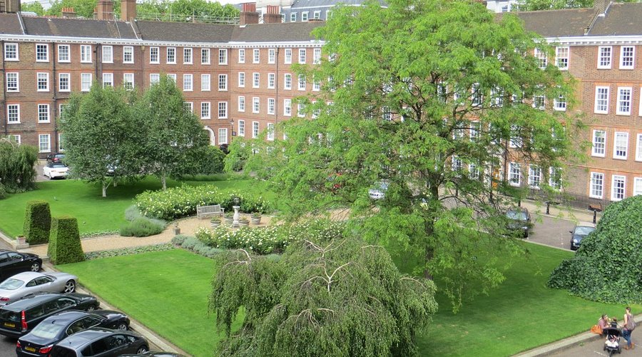 photograph of lawns and trees surrounded on at least two sides by a four-storey red-brick building