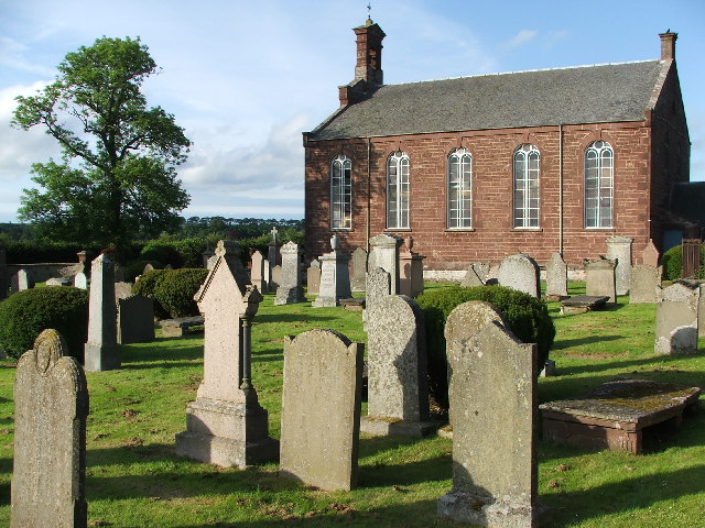 small, blocky red-brick church seen across a graveyard